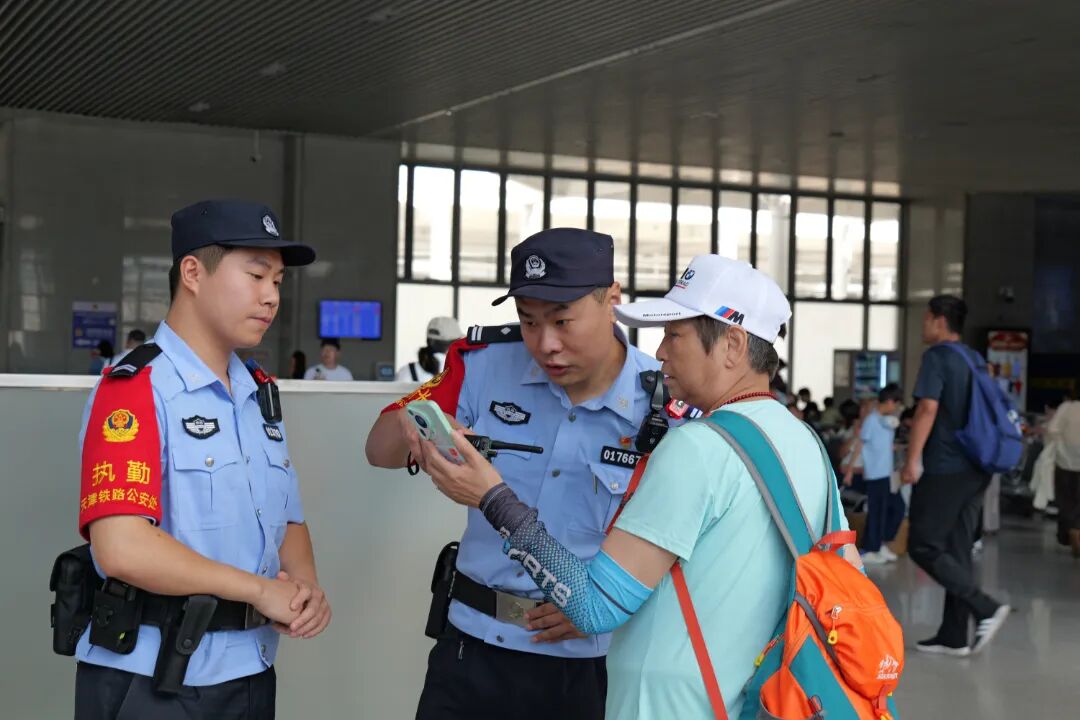 天津铁路公安处秦皇岛站派出所民警正在解决旅客的问询。.JPG